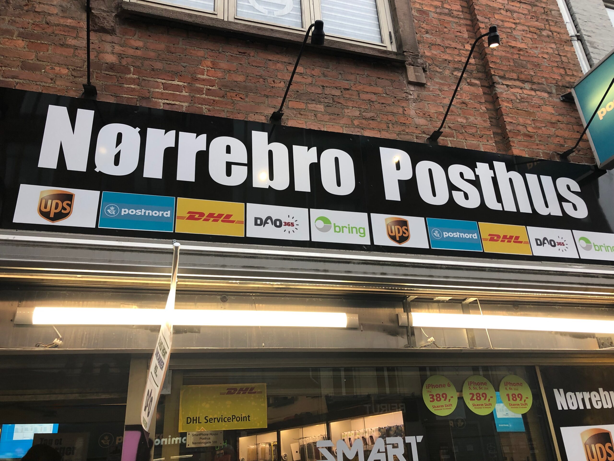 Foto af facaden ved Nørrebro Posthus med skilte for flere pakkefirmaer
